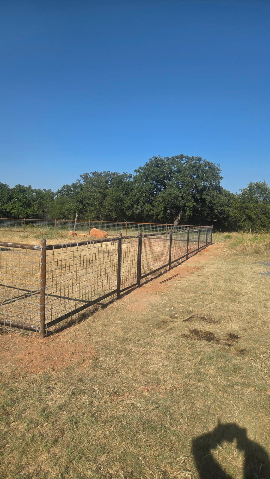 Finished 2-rail pipe fence with 4x4 wire panels across a Texas acreage property