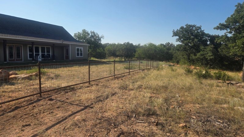Wide view of a finished 2-rail pipe fence with 4x4 wire panels in Texas