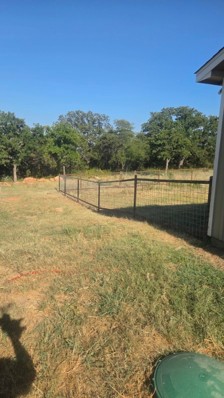 Finished welded pipe and wire-panel fence following a property line