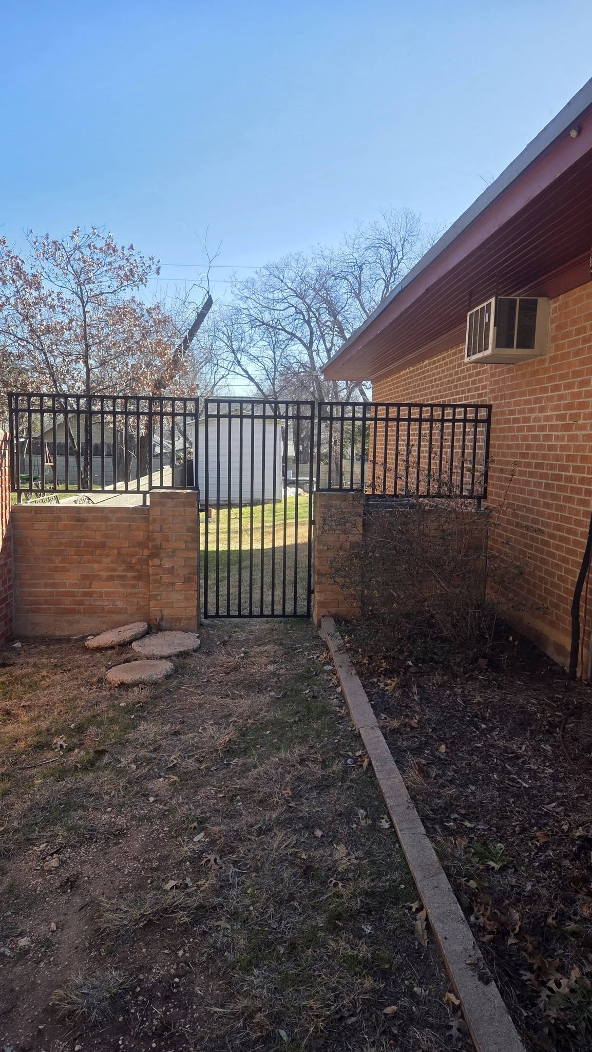 Ornamental iron entrance gate set between brick columns built by Lonestar Fencing & Welding in Texas