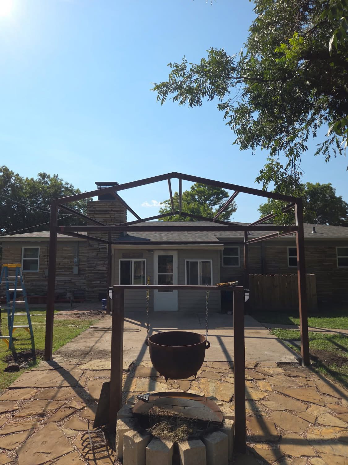 Welded steel frame under construction for a custom backyard patio cover in Texas