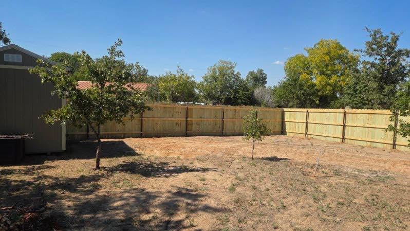 Wide view of a new wood privacy fence surrounding a Texas backyard