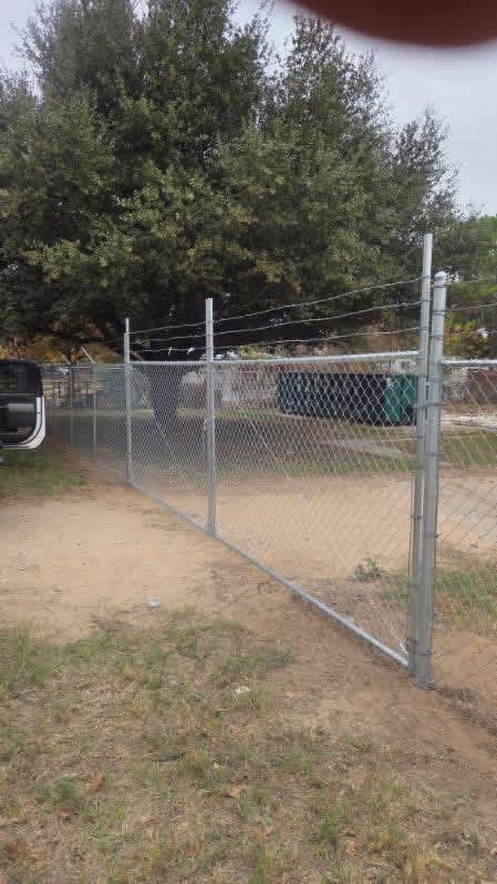 Galvanized chain-link driveway gate with security wire for a Texas property