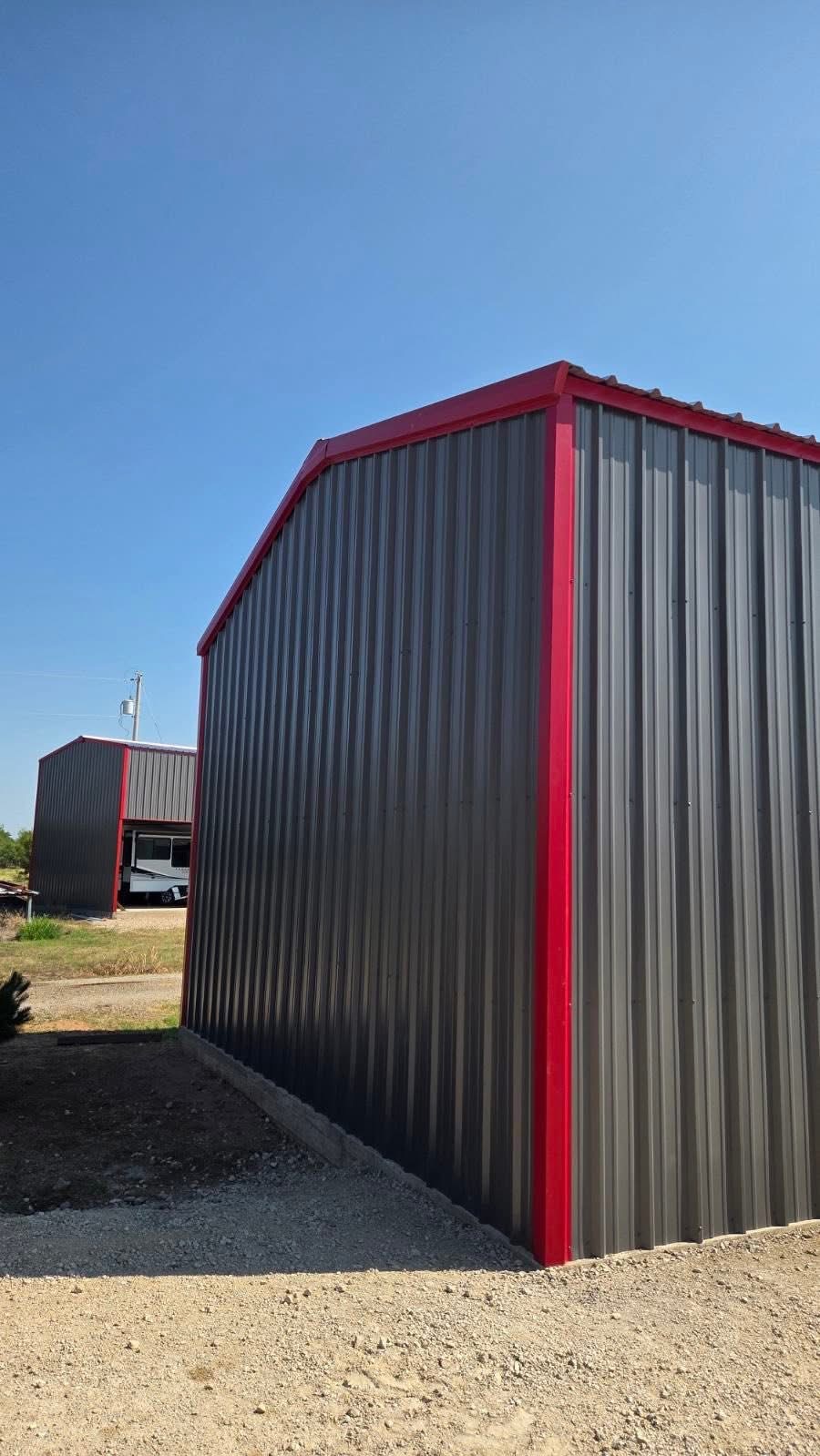 Exterior side view of a charcoal steel workshop with red corner trim in Texas