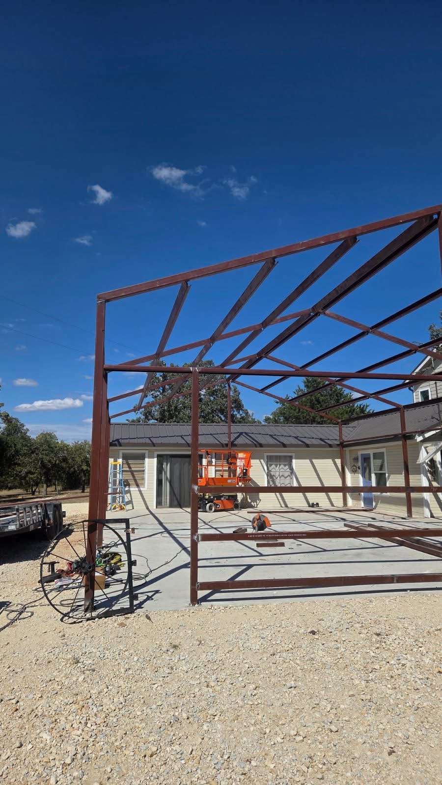Custom welded steel carport frame under construction beside a Texas home
