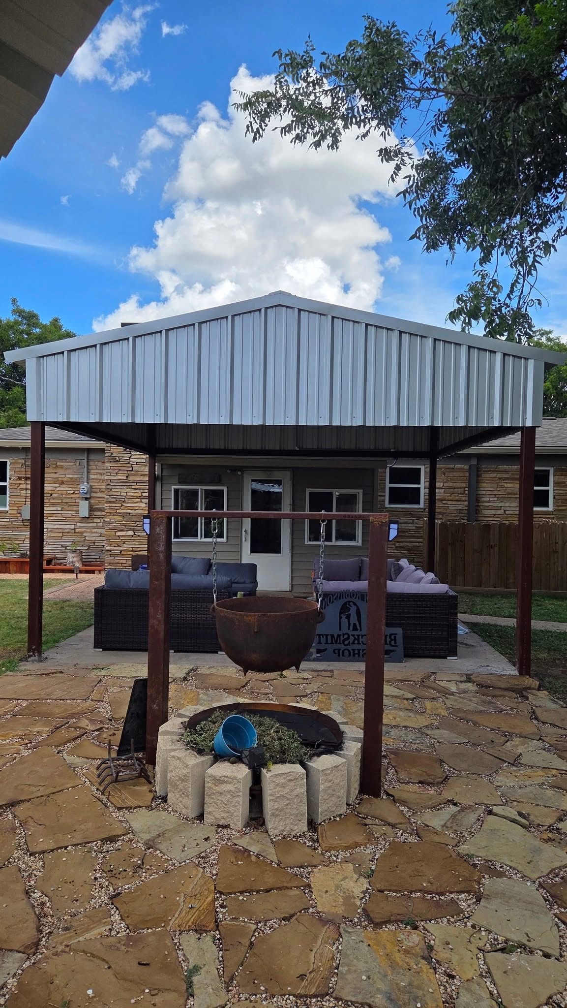 Finished gable-roof metal patio cover shading an outdoor seating area in Texas