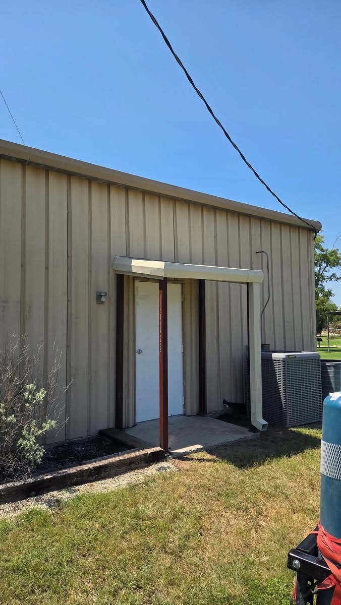 Angled view of a custom metal door awning with steel posts and roof trim
