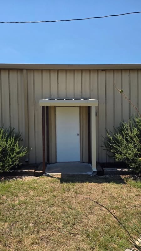 Small metal entry awning installed over an exterior door on a Texas building