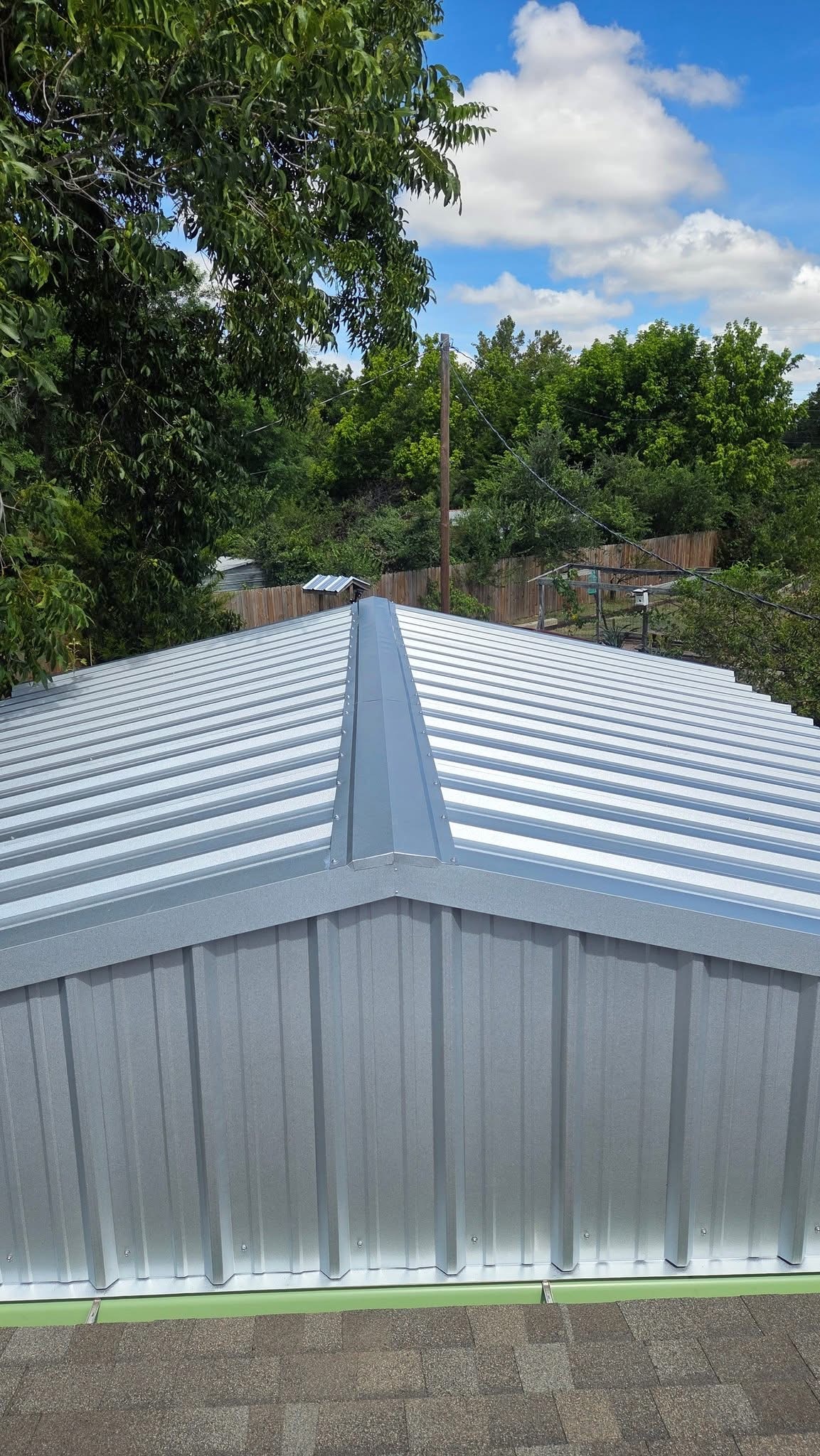 Finished silver metal patio-cover roof with ridge cap and clean trim on a Texas home