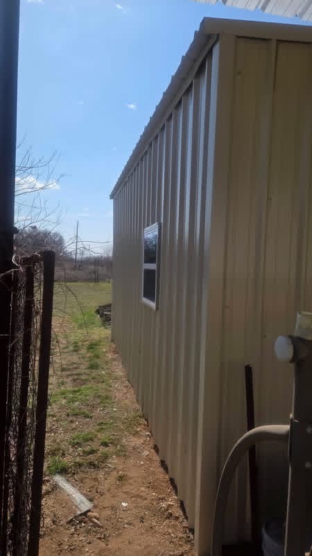 Window and exterior siding detail on a tan metal garage built in Texas