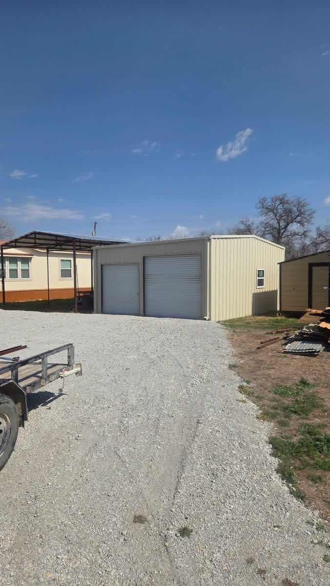 Finished two-bay metal garage with an attached steel carport in Texas