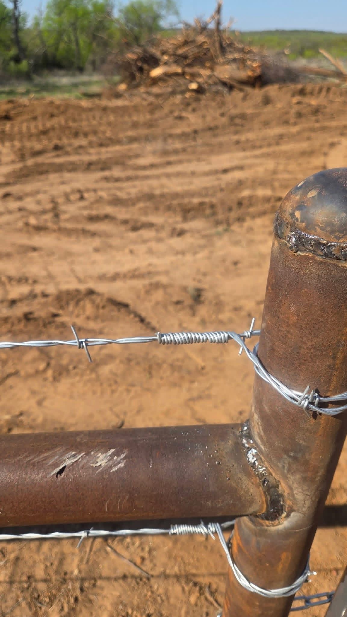 Close-up of a welded pipe H-brace securing barbed wire on a Texas ranch fence