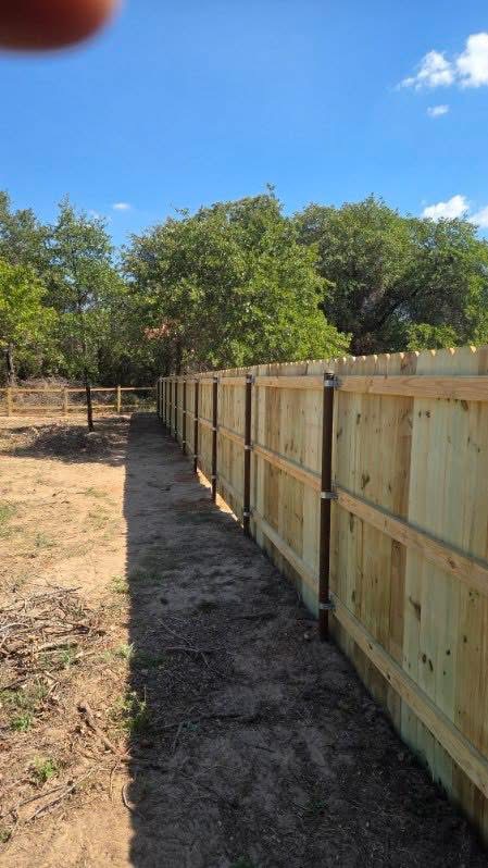 Long wood privacy fence run supported by welded steel posts on a Texas property