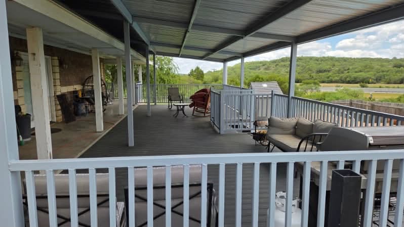 Wide view of a finished steel-framed covered metal deck with railings and outdoor seating