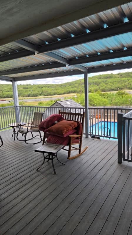 Steel-framed metal roof over a finished deck overlooking a swimming pool