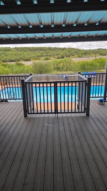 Metal railing gate opening from a covered deck to a swimming pool