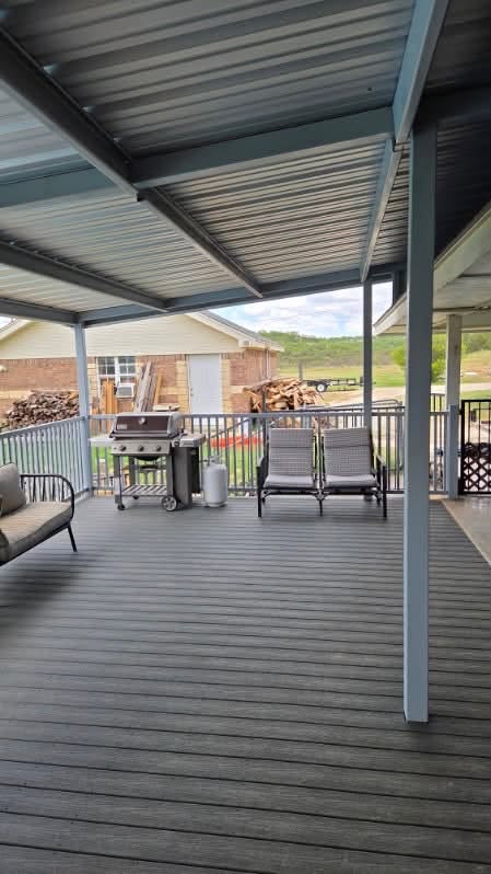 Finished covered metal deck with a grill, seating, and steel roof framing